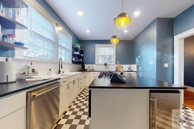 kitchen with decorative light fixtures, sink, white cabinetry, and stainless steel dishwasher