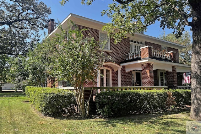 back of house featuring a balcony and a yard