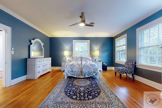 bedroom featuring ceiling fan, light hardwood / wood-style floors, multiple windows, and ornamental molding