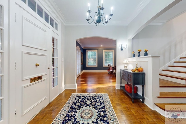 foyer entrance featuring crown molding, dark parquet floors, and an inviting chandelier