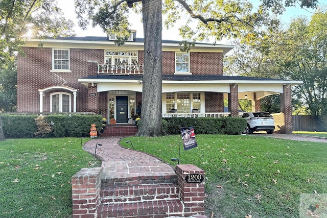 front facade featuring a balcony, a front yard, and a carport