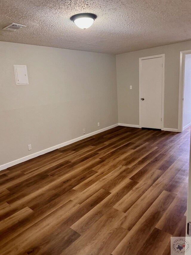 spare room with dark wood-type flooring and a textured ceiling