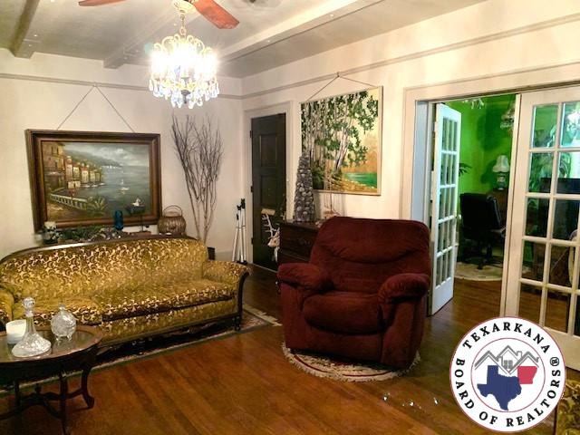 living room featuring ceiling fan with notable chandelier, beamed ceiling, and wood finished floors