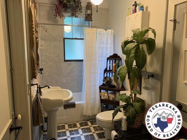 1212 Grape St, Texarkana, AR 71854 - bathroom featuring toilet, shower / tub combo, and tile patterned floors