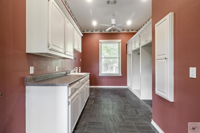 kitchen featuring ceiling fan, sink, and white cabinets