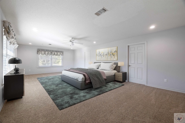 carpeted bedroom featuring ceiling fan and a textured ceiling