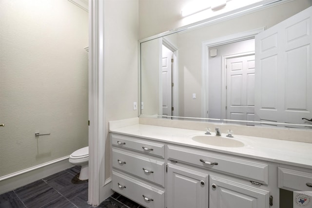 bathroom with baseboards, vanity, and toilet