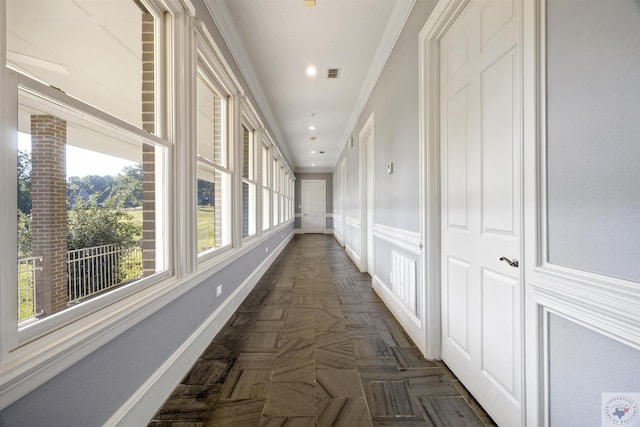 hallway featuring a decorative wall, recessed lighting, visible vents, baseboards, and crown molding