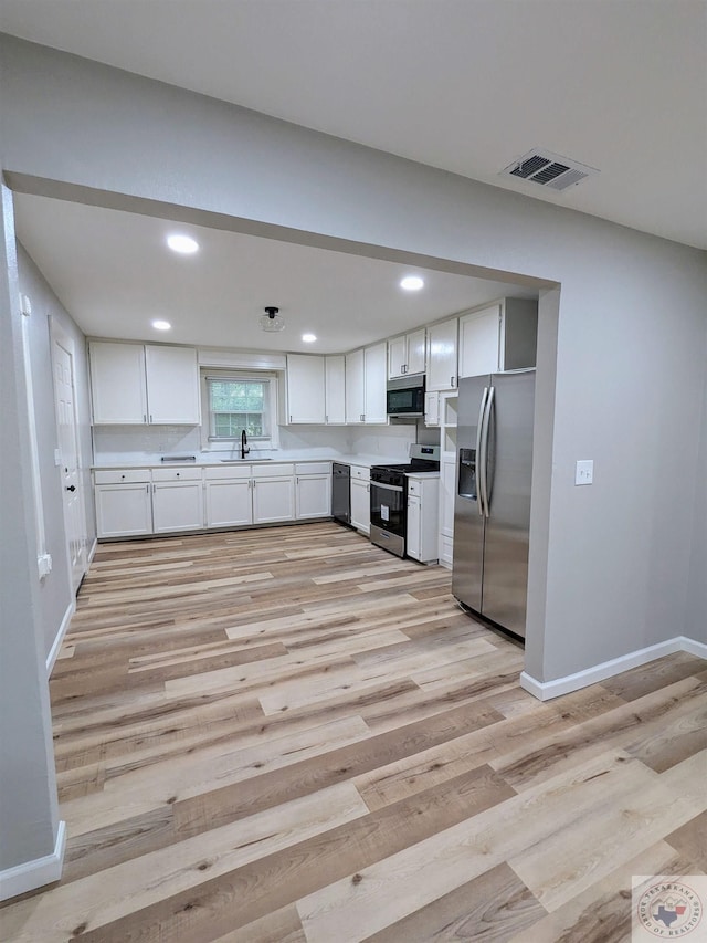 kitchen featuring sink, stainless steel appliances, white cabinetry, and light hardwood / wood-style floors