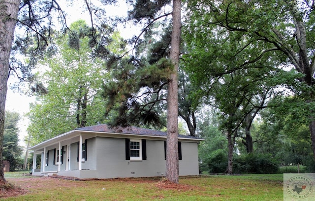 view of home's exterior with covered porch and a lawn