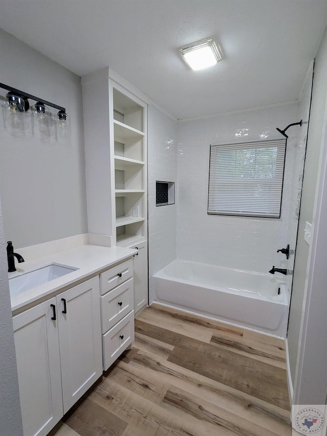 bathroom with hardwood / wood-style flooring, vanity, and tiled shower / bath combo