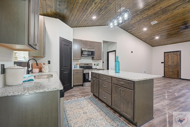 kitchen with light stone countertops, a center island, sink, stainless steel stove, and hanging light fixtures