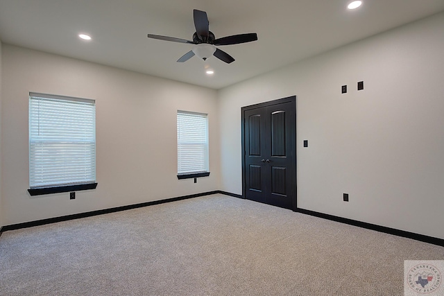 carpeted empty room with ceiling fan and a wealth of natural light