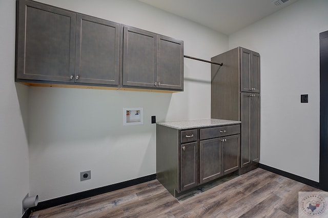 clothes washing area with hookup for a washing machine, electric dryer hookup, dark wood-type flooring, and cabinets