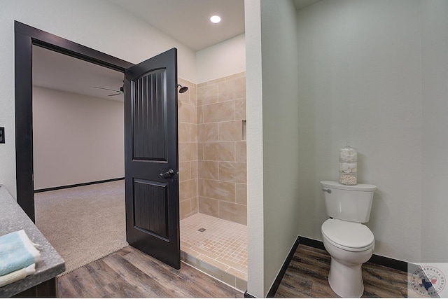 bathroom featuring hardwood / wood-style floors, tiled shower, and toilet