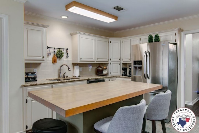 kitchen featuring a sink, stainless steel fridge, tasteful backsplash, visible vents, and butcher block counters