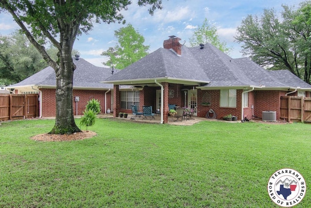 rear view of house with a chimney, fence, a lawn, and brick siding
