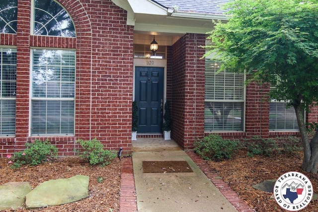 entrance to property featuring brick siding