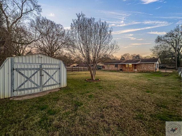 yard at dusk featuring a storage shed