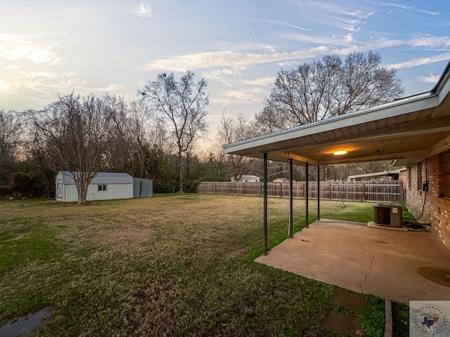 yard at dusk with a patio, central AC, and a shed