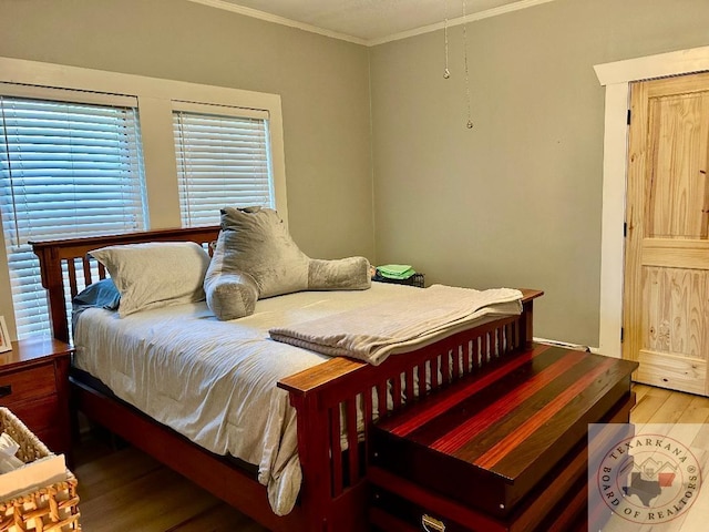 bedroom featuring wood finished floors and crown molding