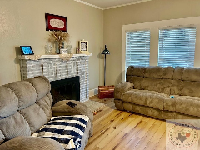 living area featuring ornamental molding, a brick fireplace, wood finished floors, and baseboards