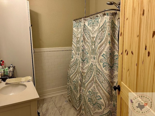 bathroom with a wainscoted wall, vanity, tile walls, marble finish floor, and a shower with curtain