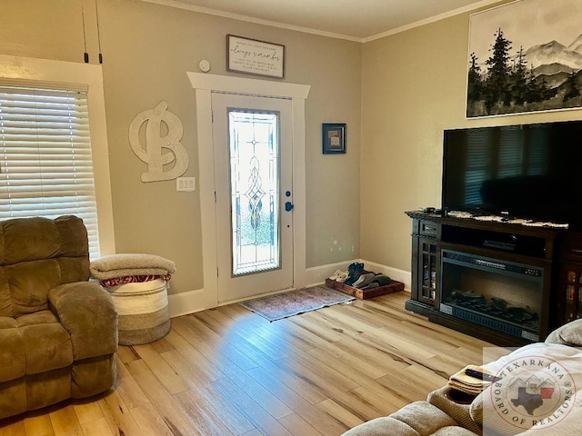 foyer featuring light wood-style flooring, a fireplace, baseboards, and crown molding