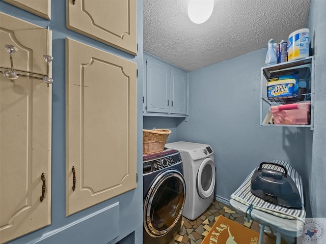 laundry area featuring cabinets, a textured ceiling, and washing machine and clothes dryer