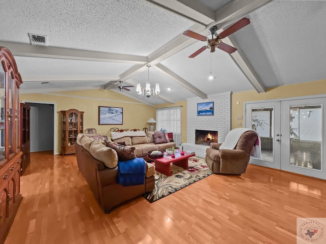 living room with a textured ceiling, french doors, lofted ceiling with beams, light wood-type flooring, and a brick fireplace