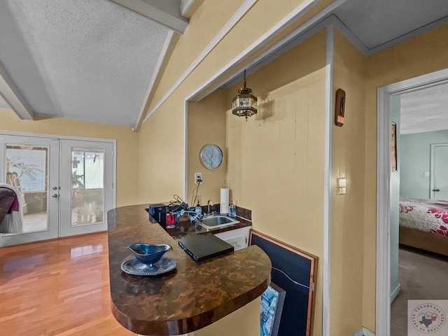 interior space with french doors, sink, lofted ceiling with beams, hardwood / wood-style floors, and a textured ceiling