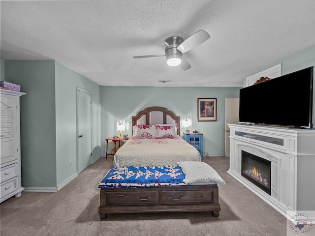 carpeted bedroom with ceiling fan and a textured ceiling