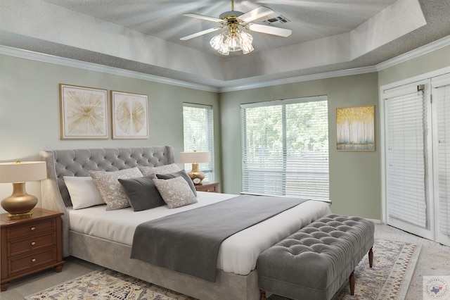 carpeted bedroom featuring ceiling fan, ornamental molding, and a tray ceiling