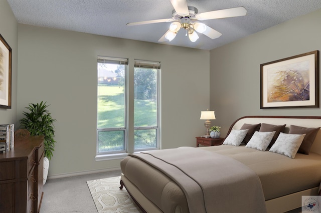 carpeted bedroom featuring ceiling fan and a textured ceiling