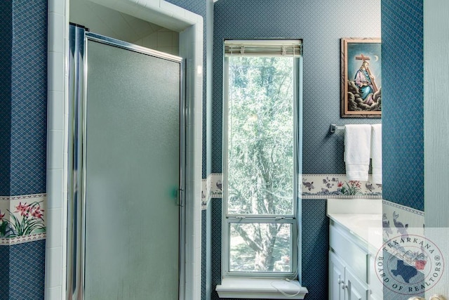 bathroom featuring a shower with shower door and vanity