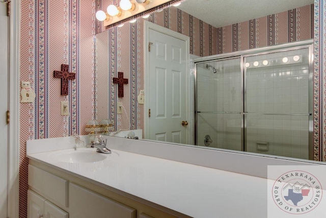 bathroom featuring a shower with door and vanity