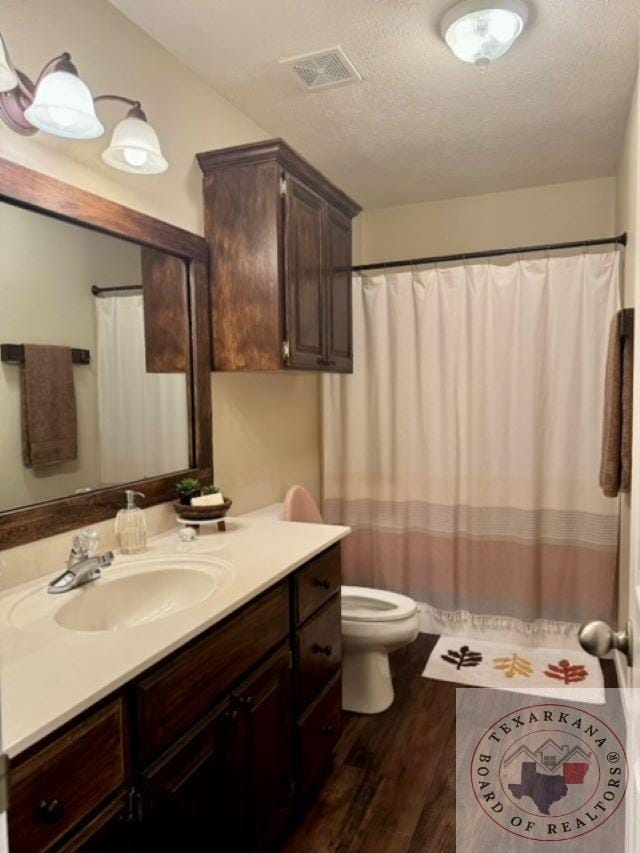 bathroom with vanity, toilet, hardwood / wood-style floors, and a textured ceiling