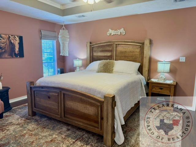 bedroom with ornamental molding, ceiling fan, and a raised ceiling