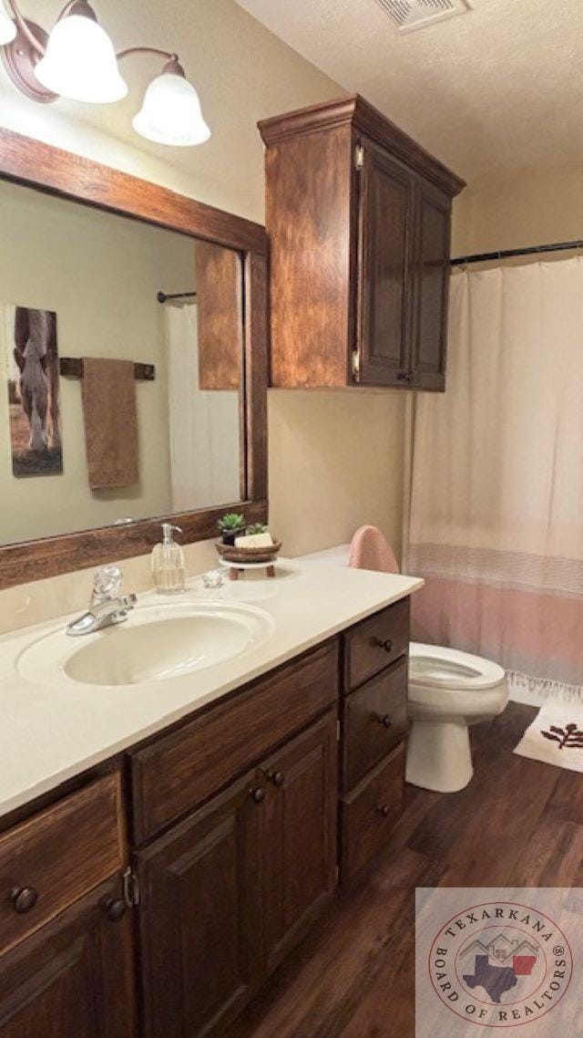 bathroom with a textured ceiling, hardwood / wood-style flooring, toilet, and vanity