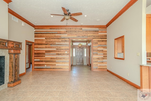 unfurnished living room featuring a textured ceiling, a fireplace, wooden walls, ceiling fan, and crown molding