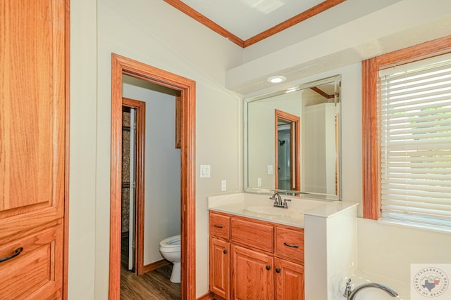 bathroom featuring wood-type flooring, toilet, vanity, and ornamental molding