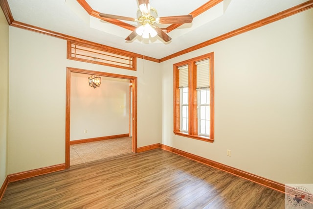 spare room with hardwood / wood-style flooring, a raised ceiling, ceiling fan, and ornamental molding