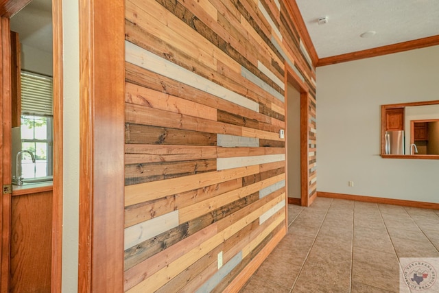 hall featuring sink, wooden walls, light tile patterned floors, and crown molding