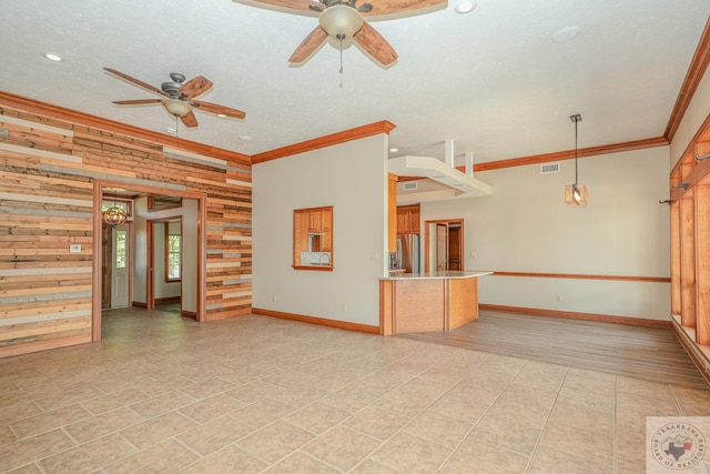 unfurnished room with ceiling fan, a textured ceiling, ornamental molding, and wooden walls