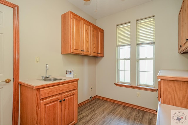 laundry room with sink, light hardwood / wood-style flooring, hookup for a washing machine, electric dryer hookup, and cabinets