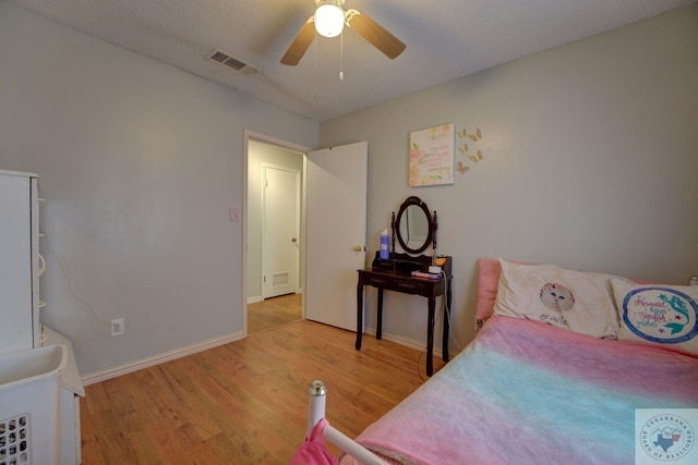 bedroom with a textured ceiling, light hardwood / wood-style flooring, and ceiling fan