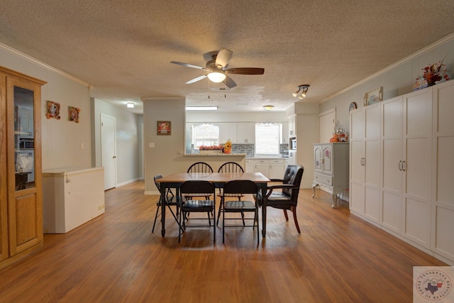 dining space featuring ceiling fan, hardwood / wood-style floors, crown molding, and a textured ceiling