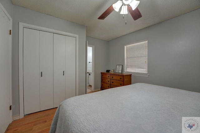 bedroom with ceiling fan, light wood-type flooring, a textured ceiling, ensuite bath, and a closet