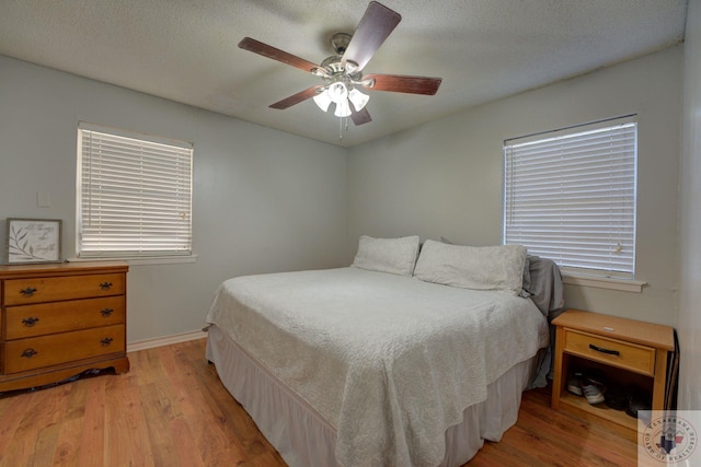 bedroom with light wood-type flooring, ceiling fan, and a textured ceiling