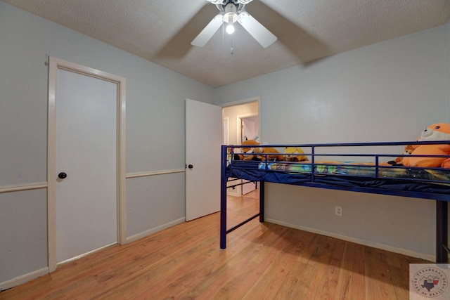 bedroom with ceiling fan, a textured ceiling, and light wood-type flooring